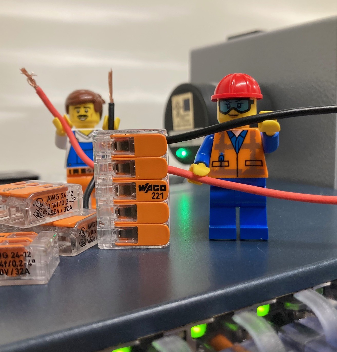 Two LEGO minifigures set up to look like electricians working on electrical wiring.
